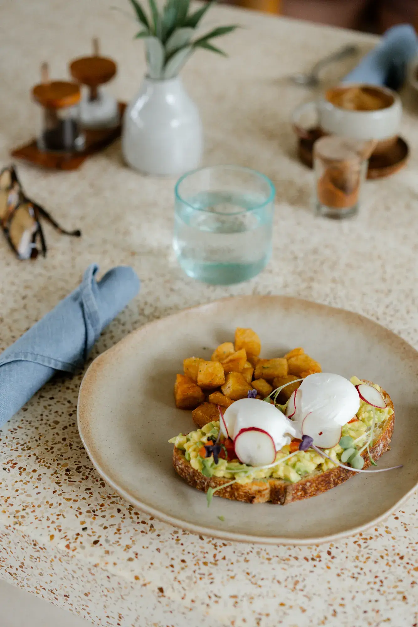 Poached eggs on toast with sliced radish and breakfast potatoes at Boni Beach.