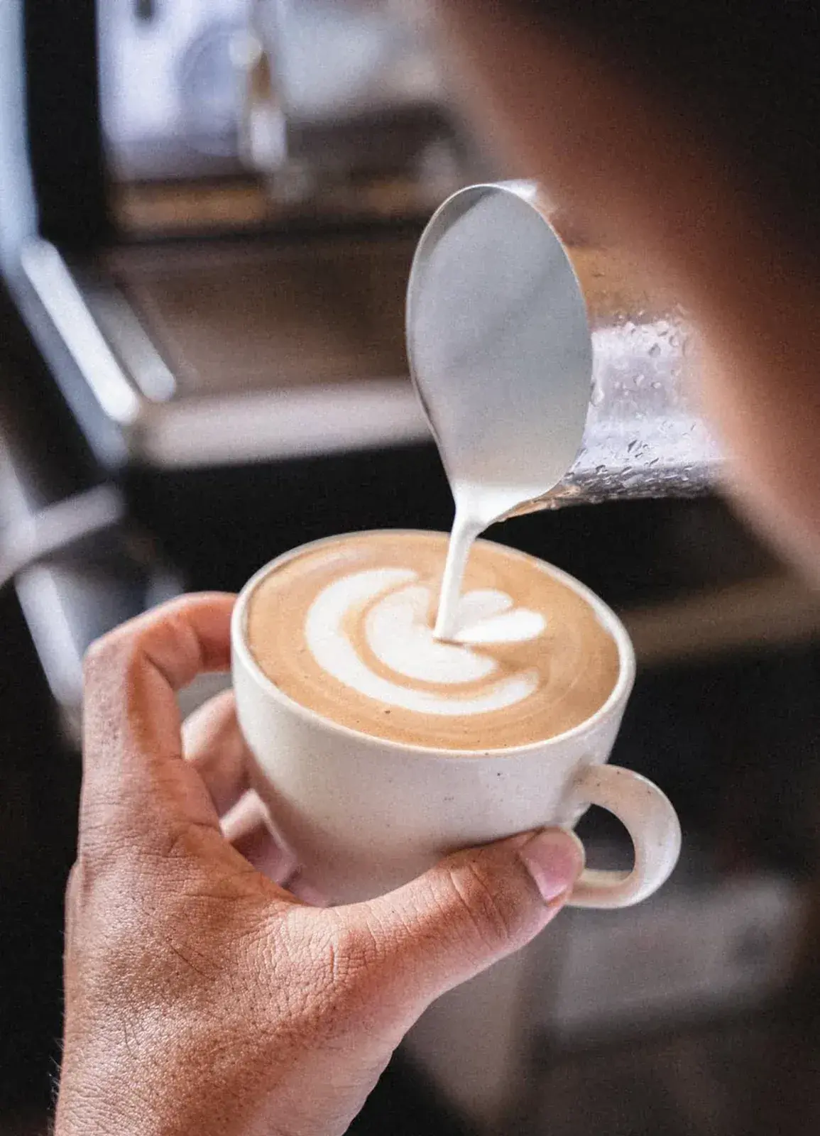 Milk being poured into a ceramic cup to make latte art at Bagi Coffee & Eatery.
